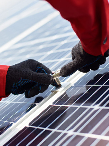 installing solar panels closeup mans hands orange uniform black gloves with wrench his hands